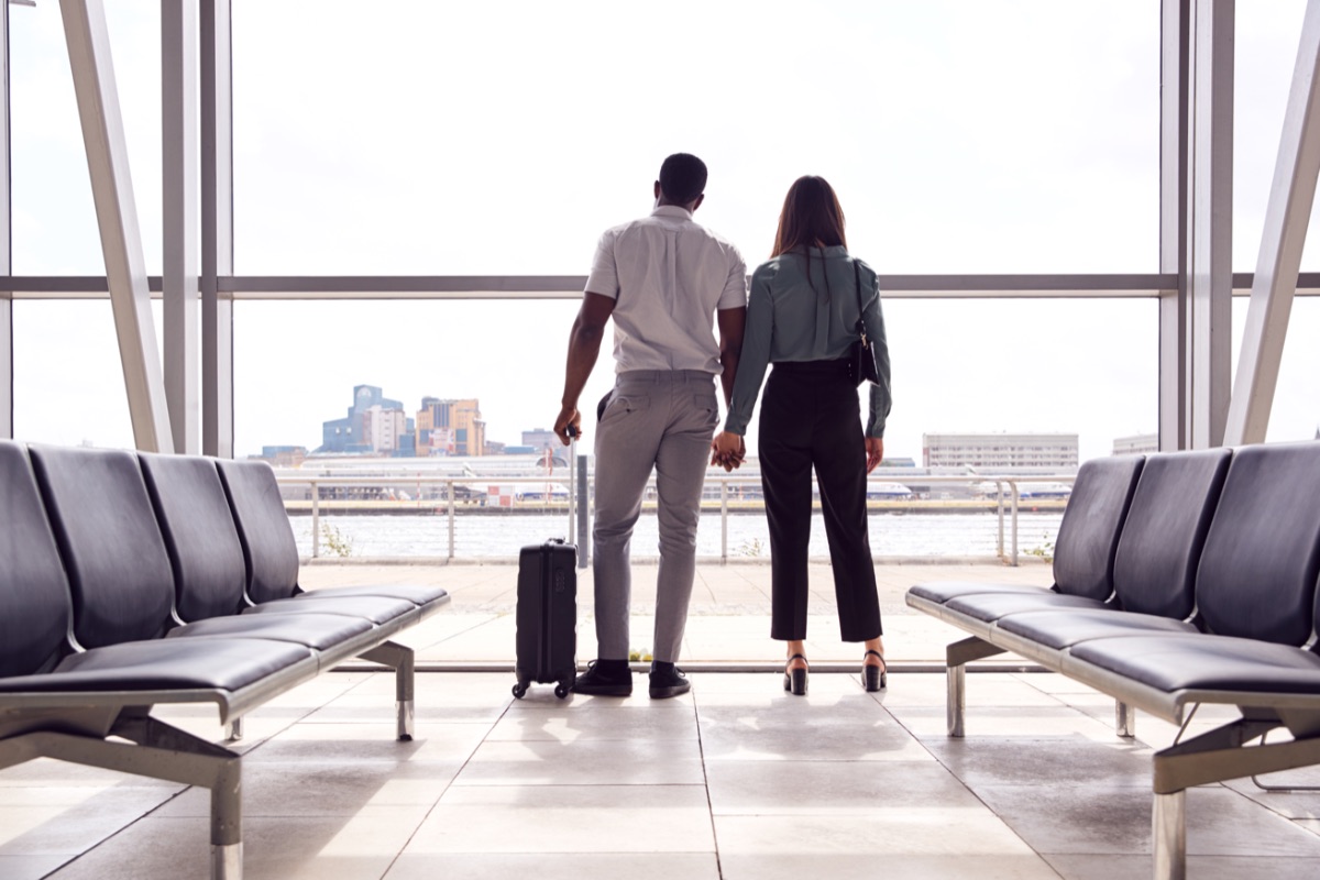 rear-view-of-business-couple-with-luggage-standing-ZU3PZUW-2